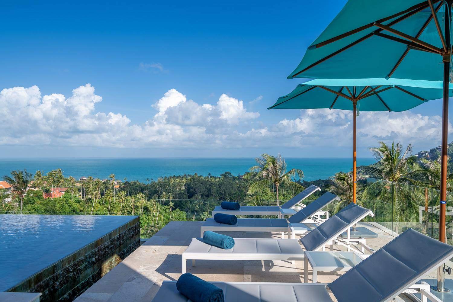 Rooftop infinity pool terrace with umbrellas and sea view, Aruna