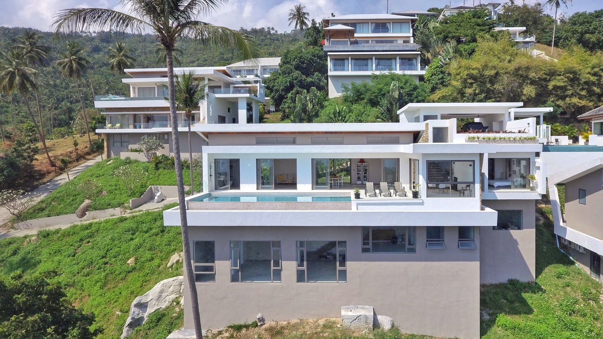 Ultra — dining terrace opening through floor-to-ceiling glass to the infinity pool and sea, Koh Samui